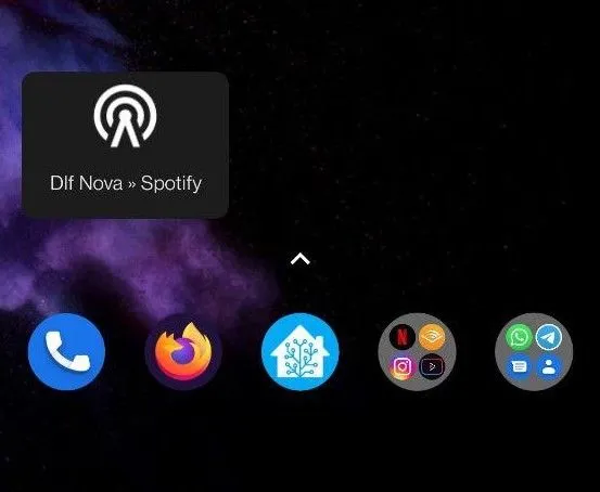 Android home screen showing a Home Assistant widget labeled "Dlf Nova » Spotify" with a radio tower icon, with app icons in the dock including Phone, Firefox, and Home Assistant against a dark purple nebula wallpaper